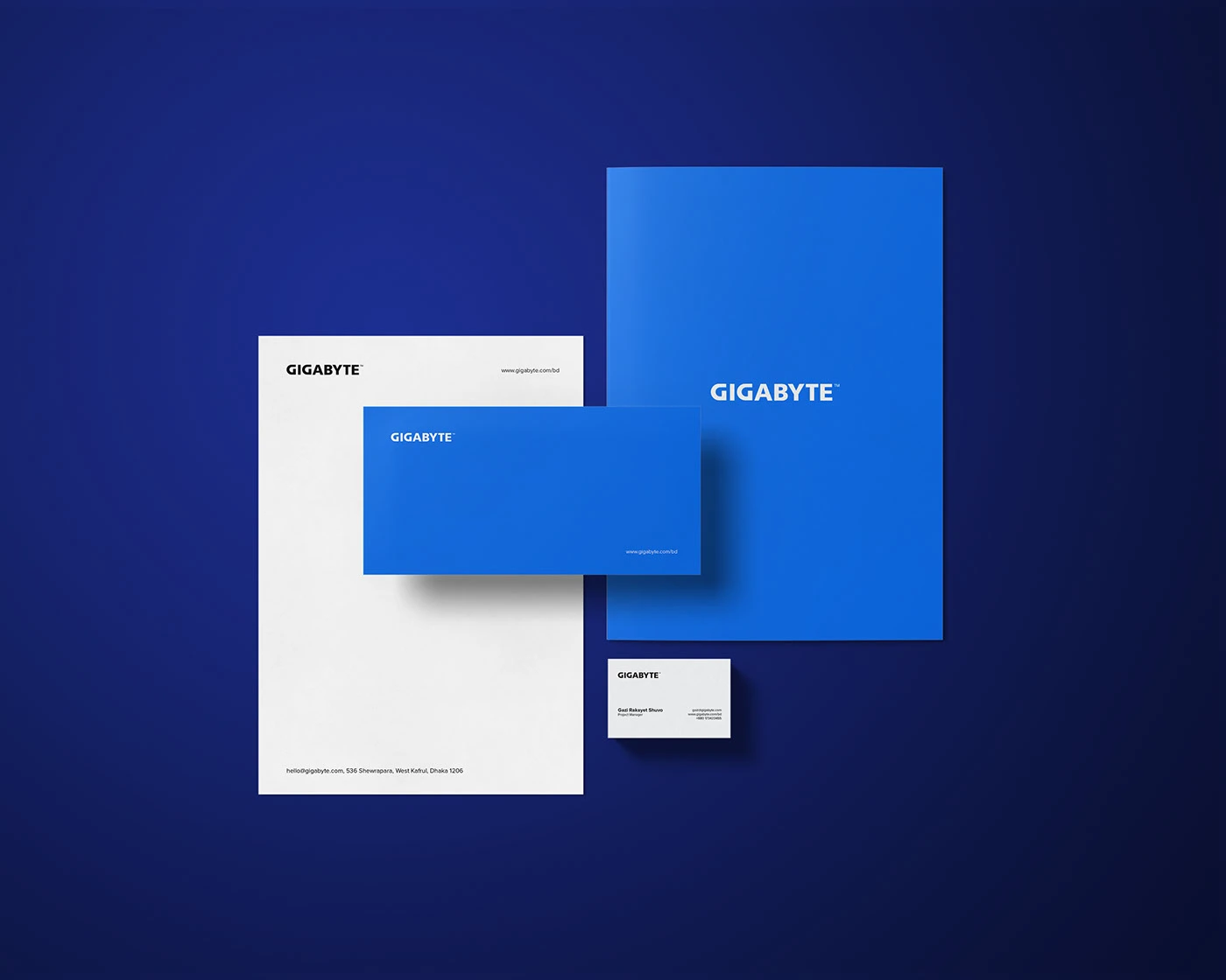 A complete set of GIGABYTE corporate stationery on a dark blue background, including a letterhead, a blue folder, a large blue card, and a small business card.